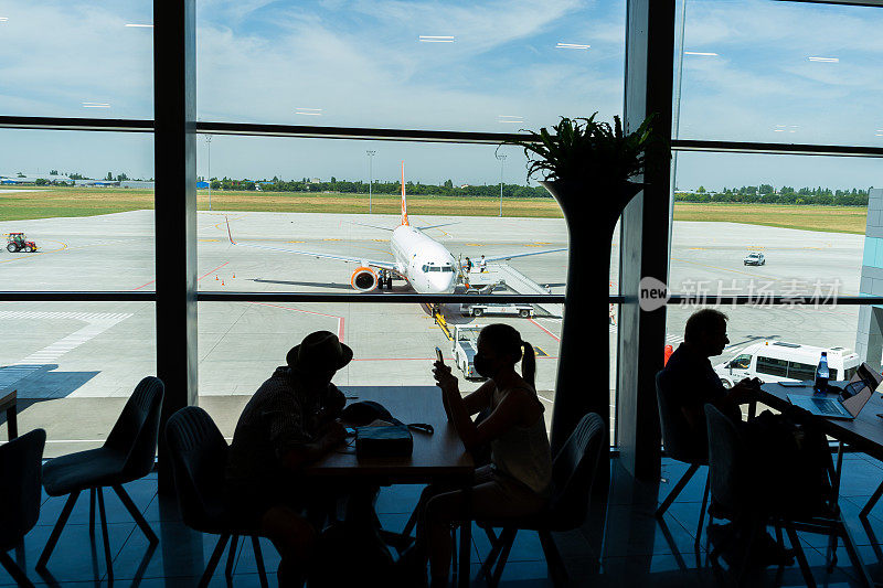 敖德萨机场。在飞机起飞前的候机楼里。Odesa ODS机场。戴面具的人在等着登机。旅客们在机场候机室等候